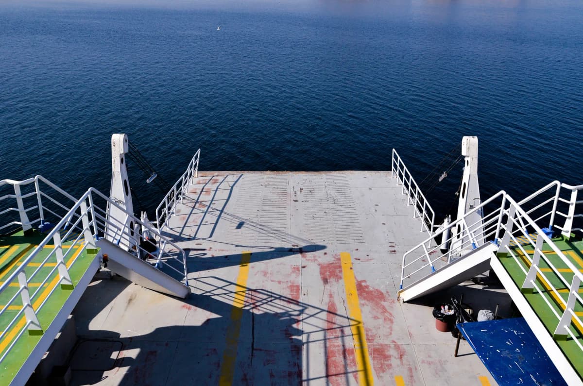 An empty ferry deck overlooking the calm ocean on a sunny day.
