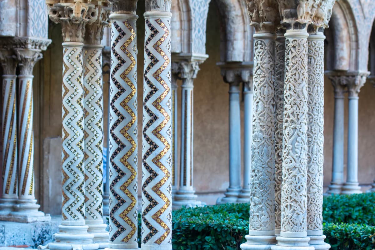 Explore the ornate columns of Monreale Cathedral's cloister in Sicily, showcasing exquisite mosaic and carving artistry.